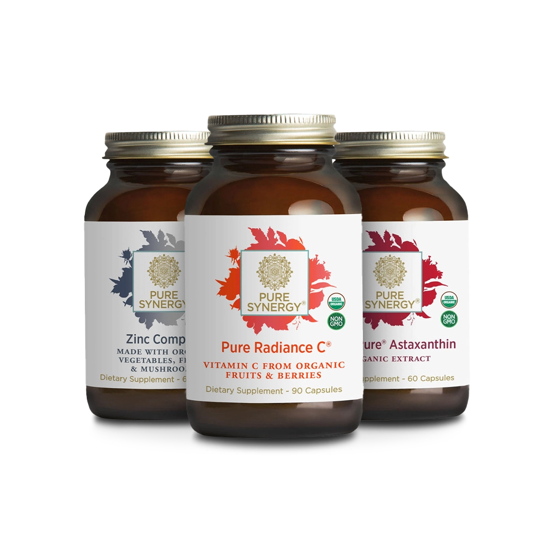 Three brown bottles of Pure Synergy supplements: Zinc Complex, Pure Radiance C, and Pure Astaxanthin, each with white labels and gold caps, are arranged side by side against a white background.