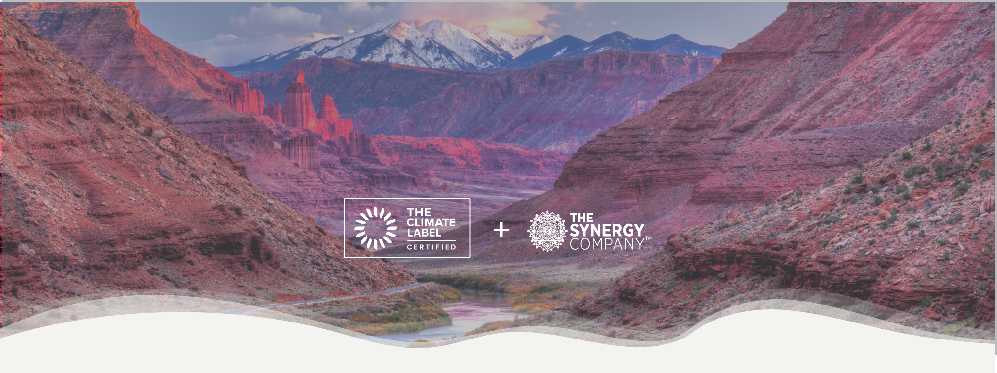 Red rock canyon landscape with river, distant snow-capped mountains, and logos for The Climate Label Certified and The Synergy Company in the foreground.