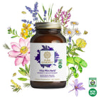 A bottle of The Synergy Company Vita•Min•Herb® For Women multivitamin, featuring organic and non-GMO certification logos, stands surrounded by vibrant illustrated flowers and herbs.